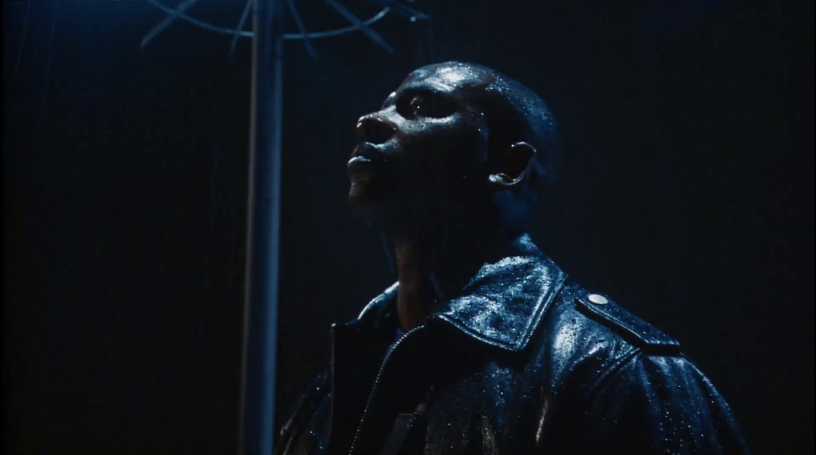 a man in a leather jacket looking up at a light