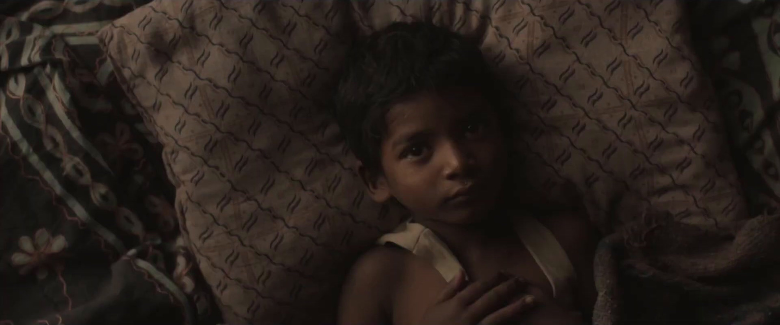 a little girl laying in a bed with a blanket