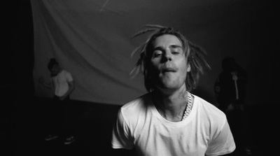 a man with dreadlocks standing in a dark room