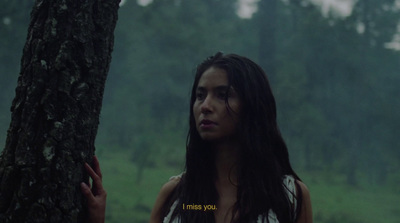 a woman standing next to a tree in a forest