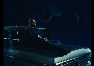 a man sitting on the hood of a pickup truck