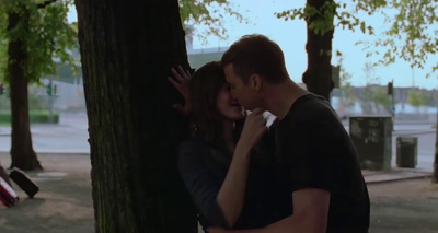 a man and a woman kissing next to a tree