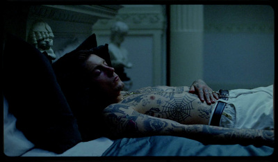 a man laying in bed with tattoos on his arms