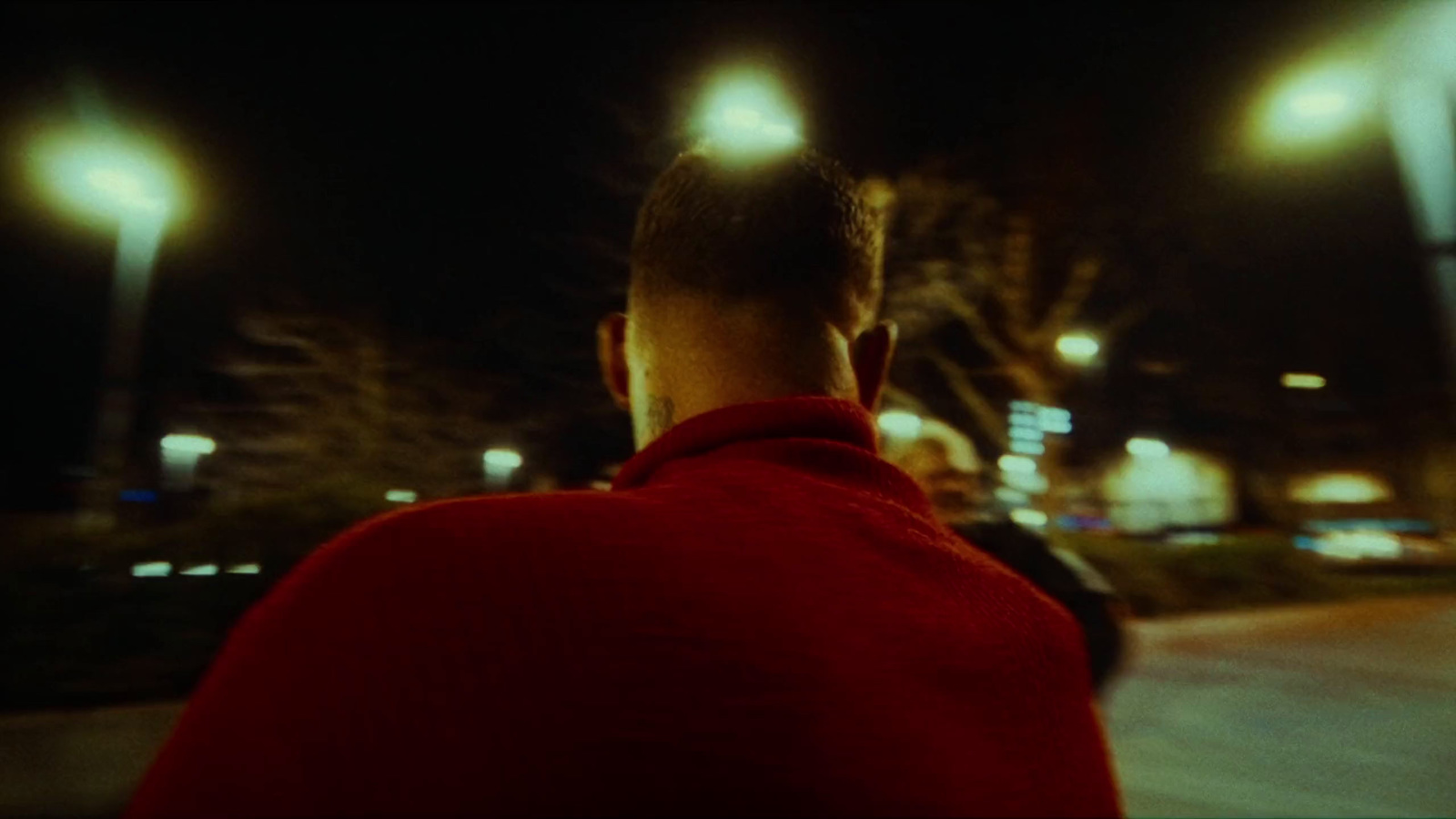 a man in a red jacket standing in the street at night