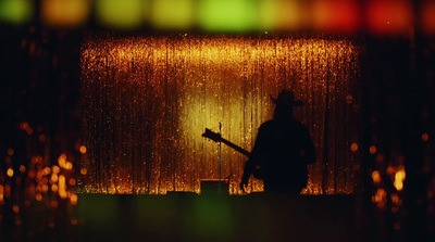 a man playing a guitar in front of a rain shower