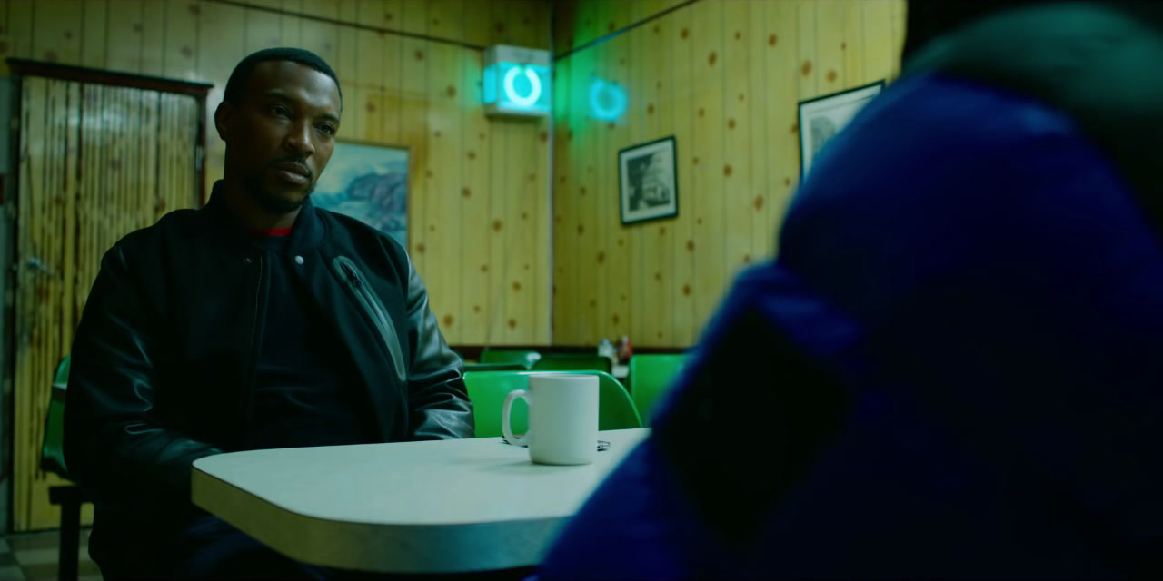 a man sitting at a table with a cup in front of him