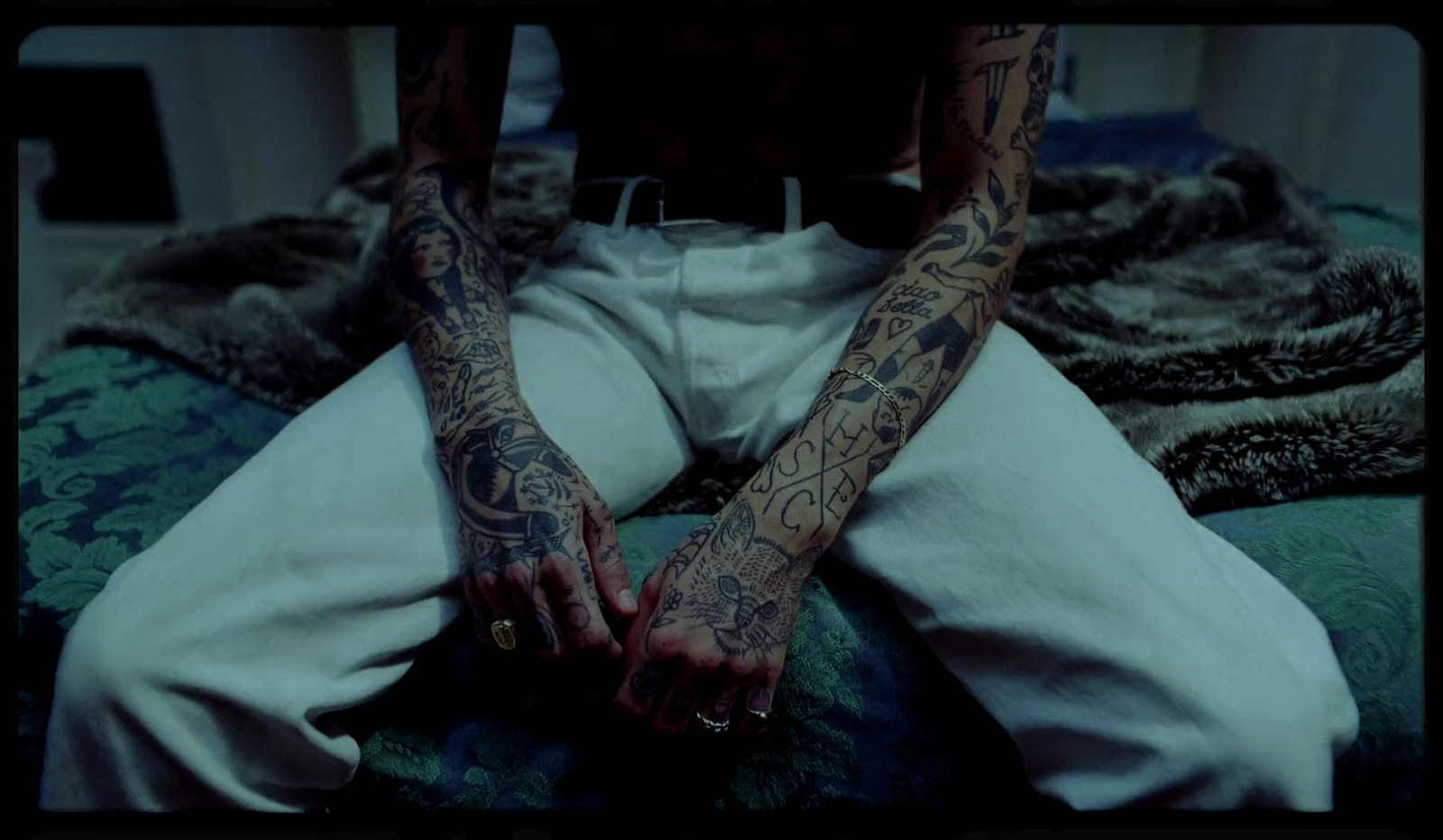 a person with tattoos sitting on a bed