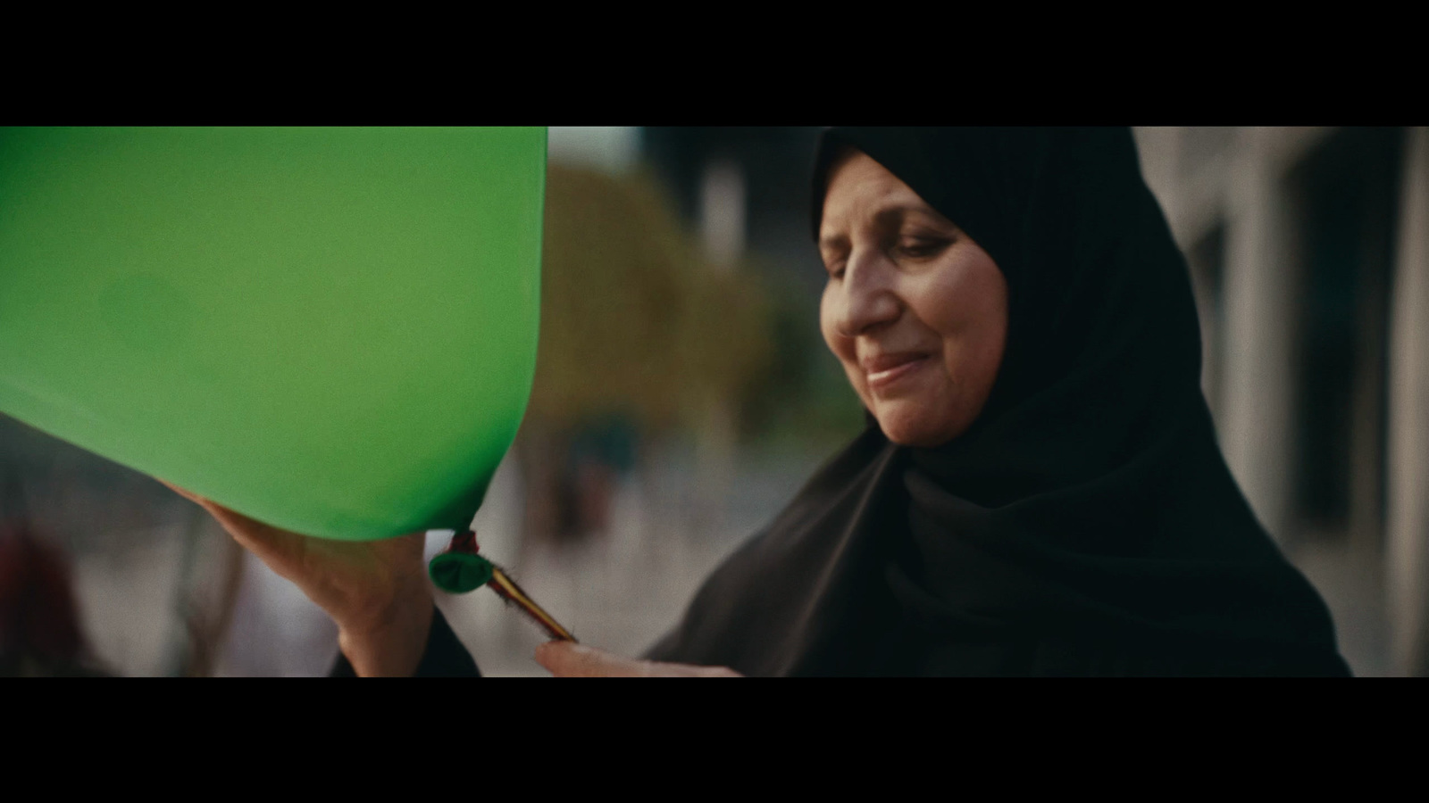 a woman in a hijab holding a green balloon