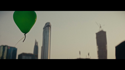 a green balloon flying over a city skyline