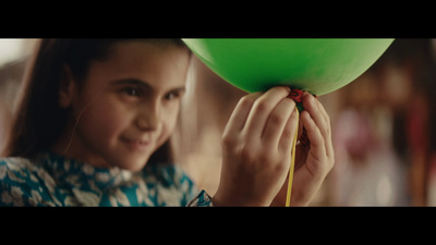 a young girl holding a green balloon in her hand