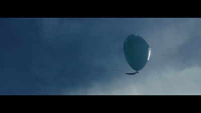 a large balloon flying through a cloudy blue sky