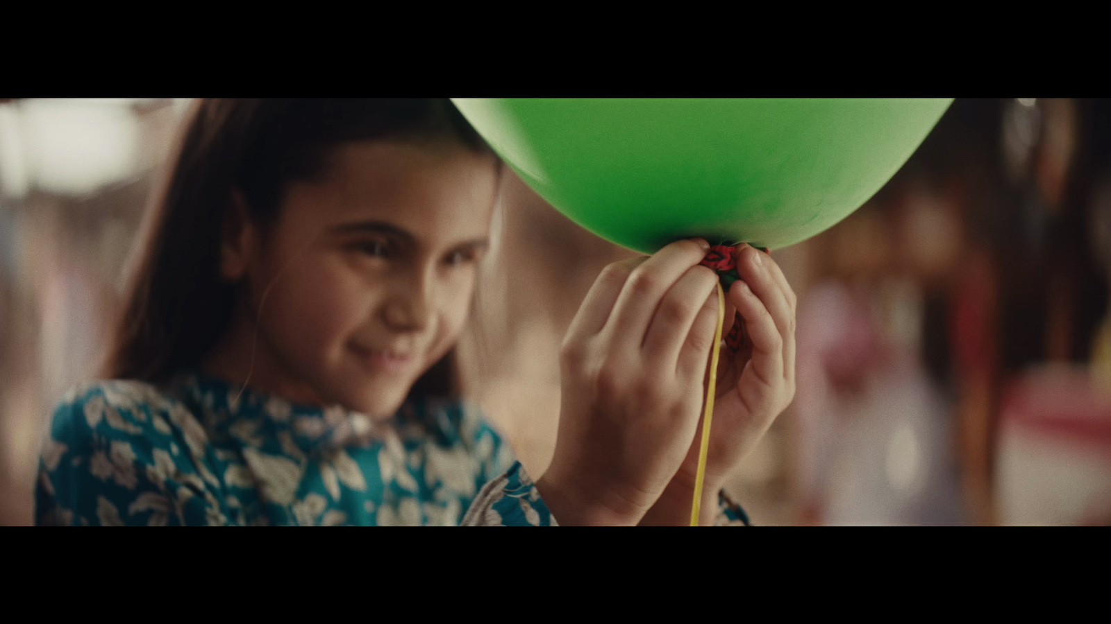 a young girl holding a green balloon in her hands