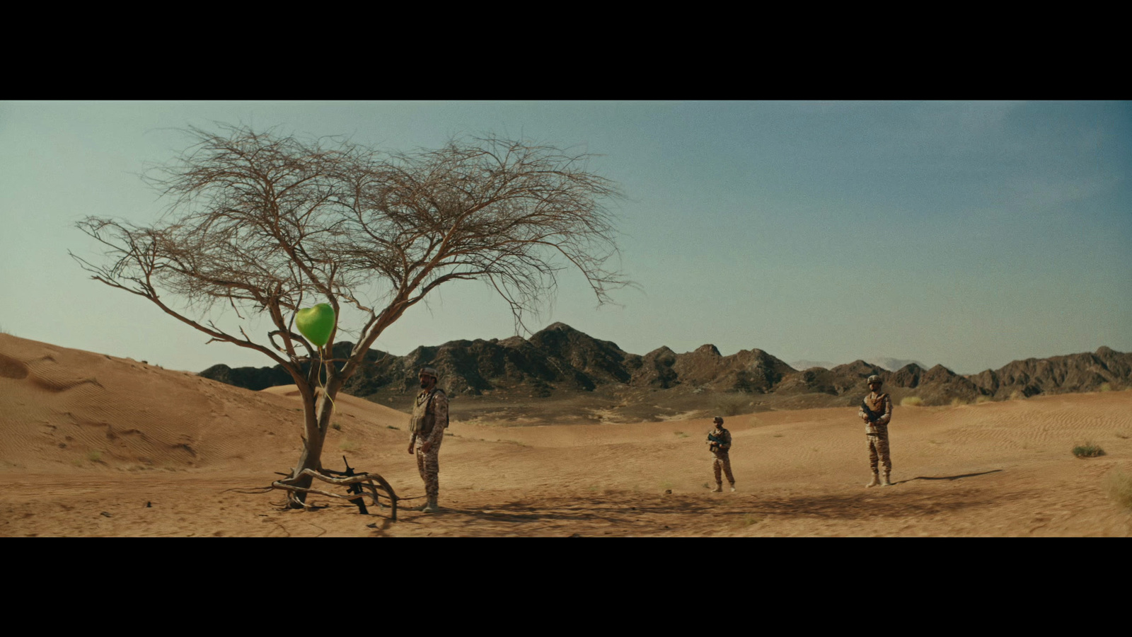 a group of people standing around a tree in the desert