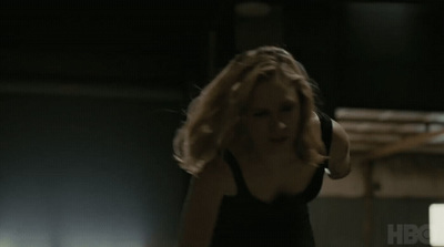 a woman in a black tank top standing in a dark room