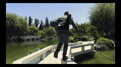 a man walking across a bridge over a lake