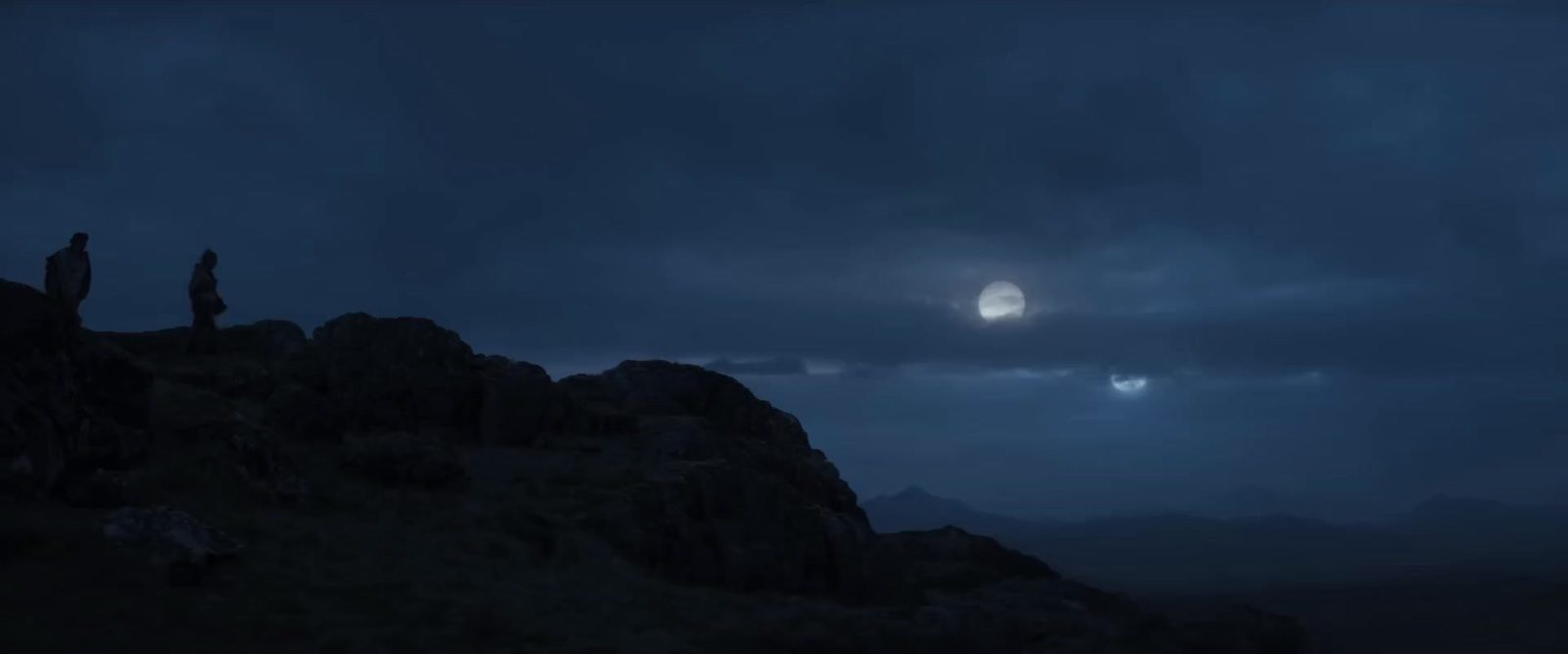 a full moon is seen over a mountain range