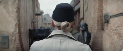 a man with a bun in his hair walking down a street