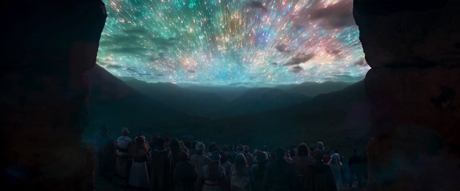 a group of people standing under a colorful sky filled with stars