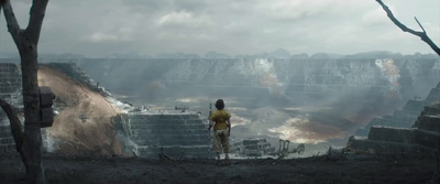 a man standing on top of a cliff next to a forest