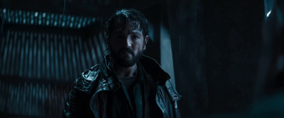 a man in a leather jacket standing in a dark room