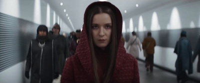 a woman in a red hoodie standing in a hallway