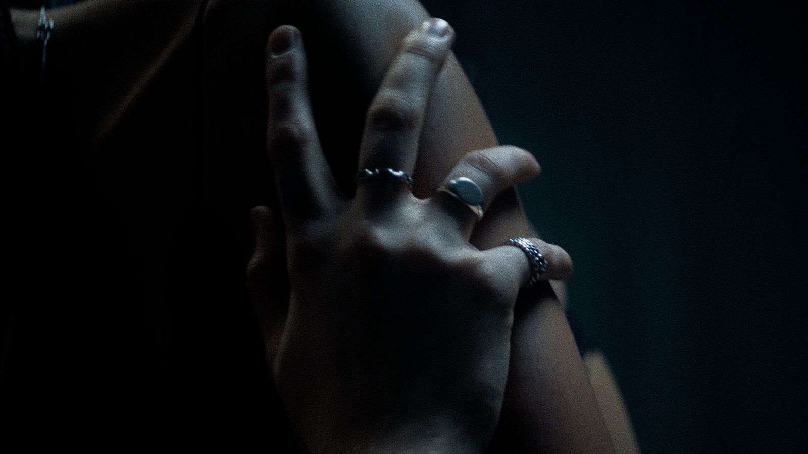 two hands with rings on their fingers in the dark