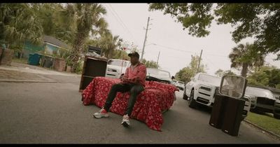 a man sitting on top of a bed covered in red sheets