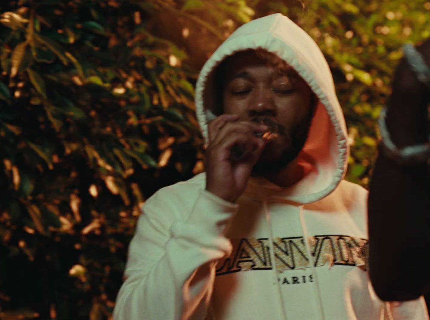 a man in a hoodie smoking a cigarette