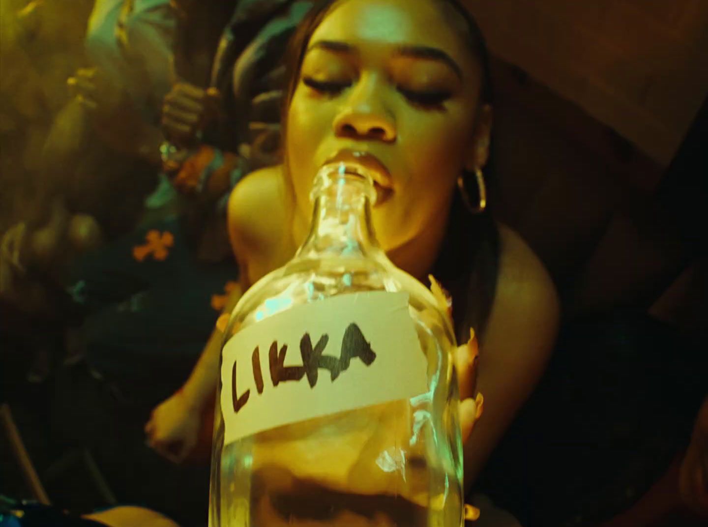 a woman drinking from a bottle with writing on it