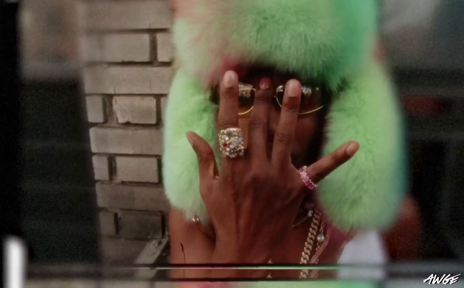 a woman wearing a green fur coat holding her hand up to her face