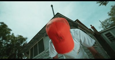 a man holding a red frisbee in front of a house