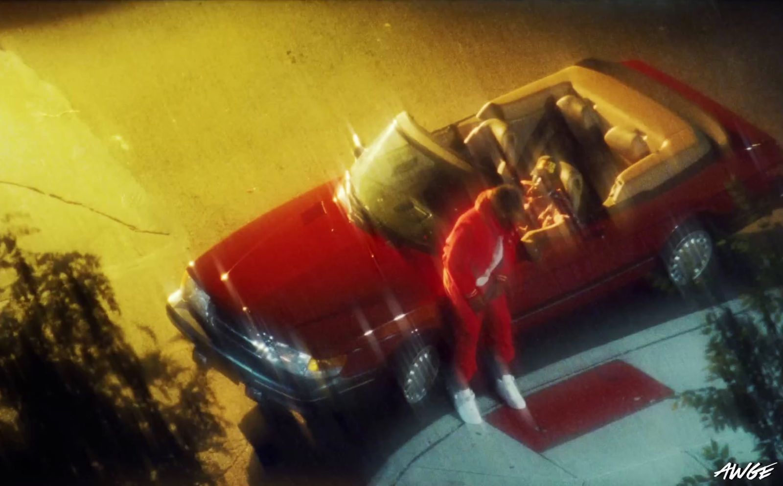 a man in a red suit standing next to a red car