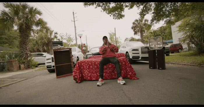 a man sitting on top of a bed in the middle of a street