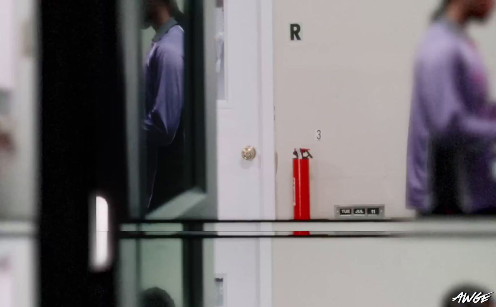 a man in a purple shirt is standing in front of a door