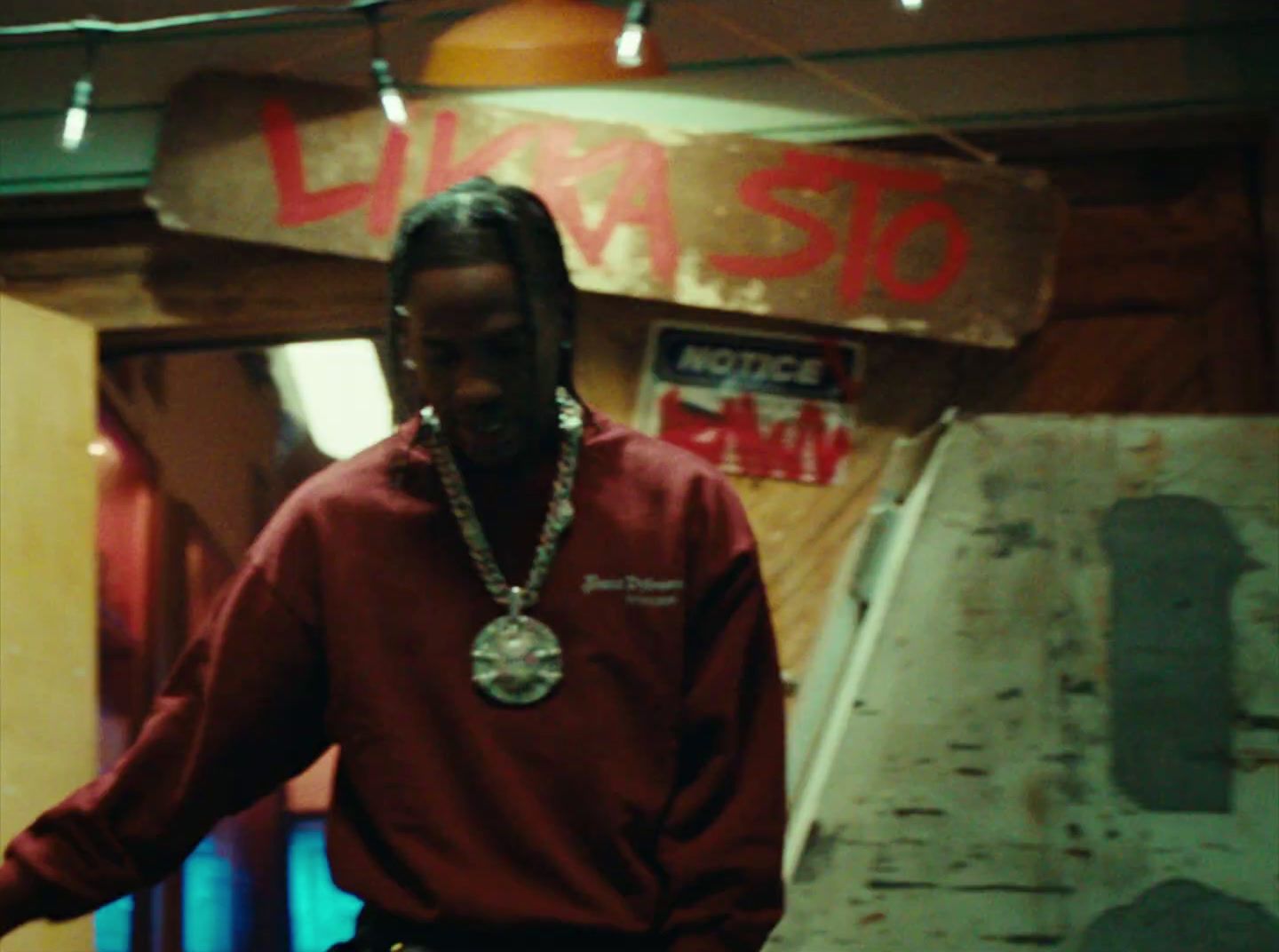 a man in a red sweatshirt is standing in front of a sign