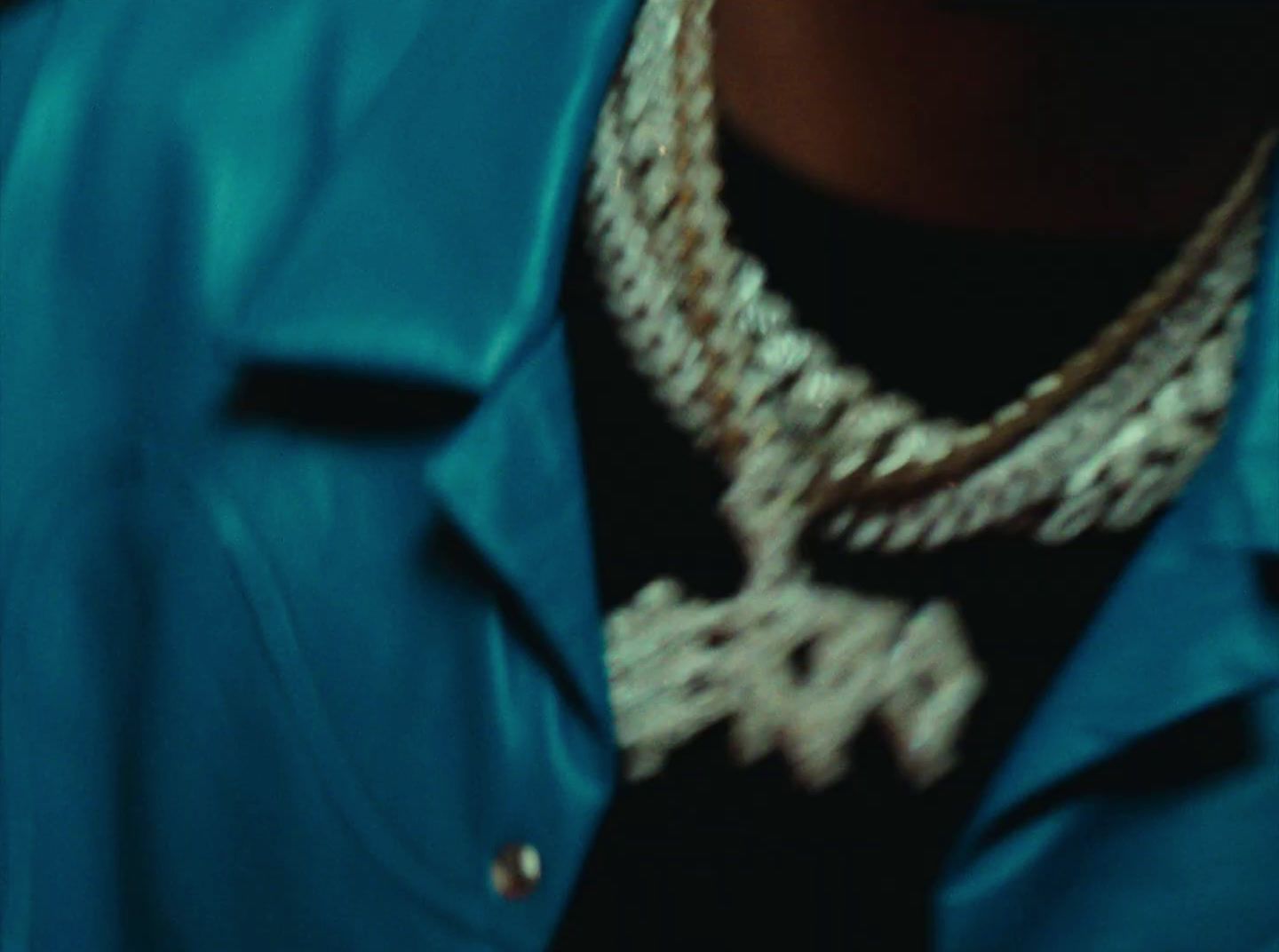 a person wearing a blue jacket and a necklace