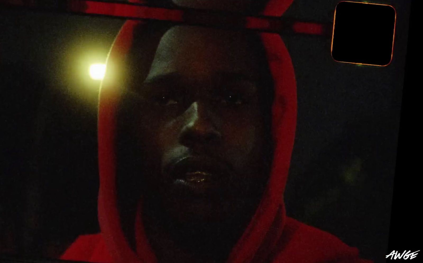 a man in a red hoodie stares into a mirror