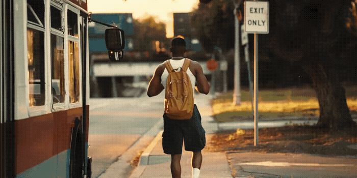 a man walking down a sidewalk next to a bus