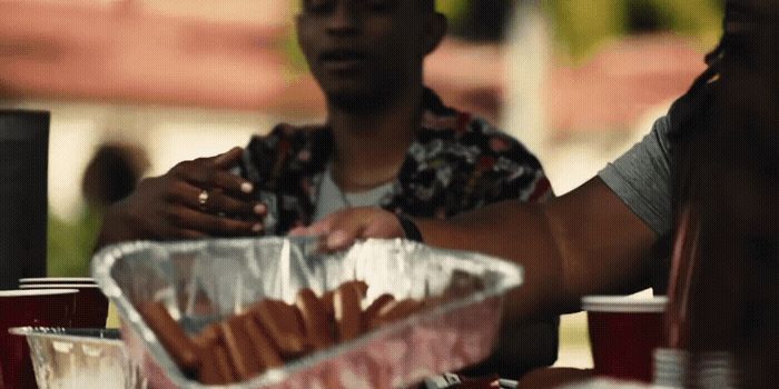 a man sitting at a table with a tray of hot dogs