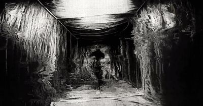 a black and white photo of a person walking down a tunnel