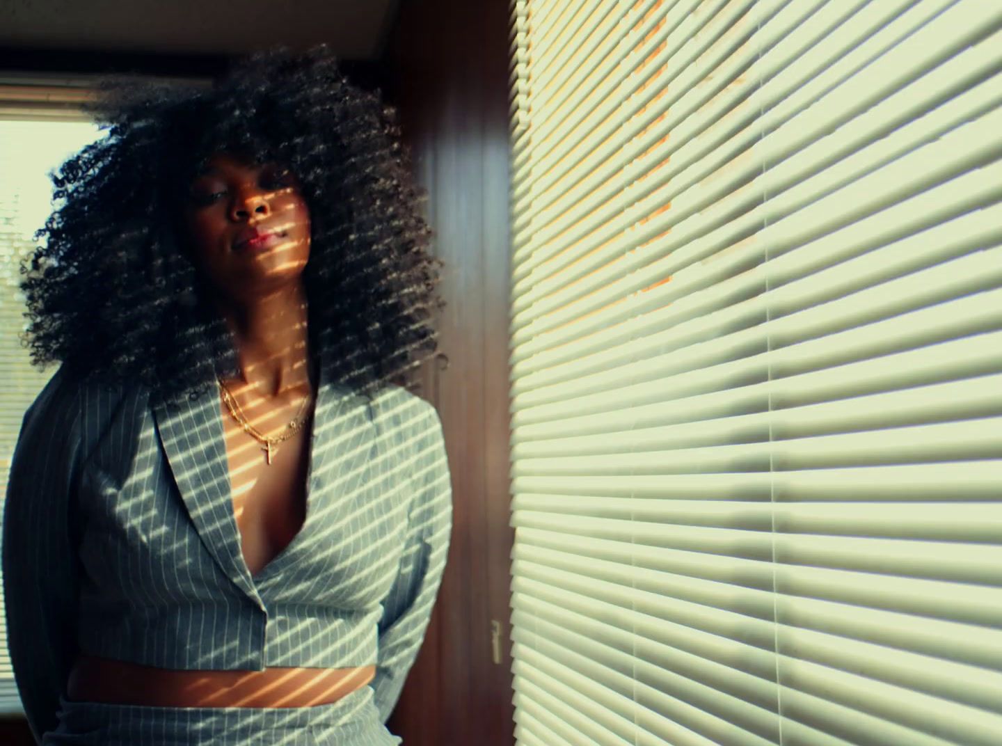 a woman standing next to a window covered in blinds