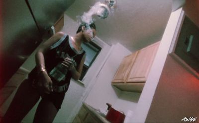 a woman standing in a kitchen smoking a cigarette