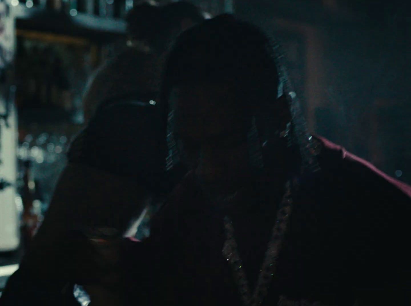 a woman standing in front of a bar in the dark