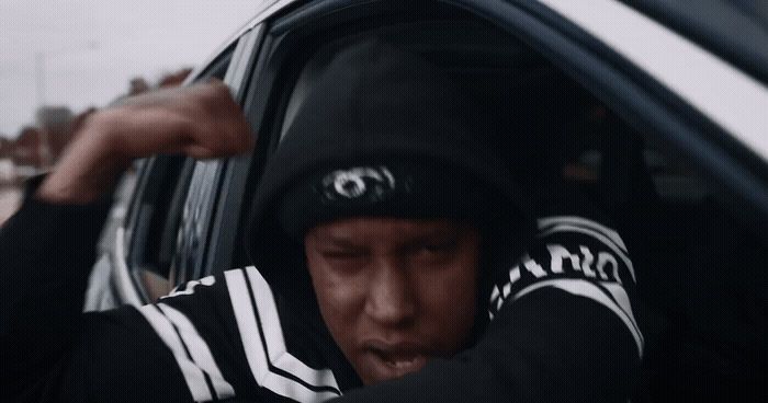 a man in a black and white hoodie sitting in a car