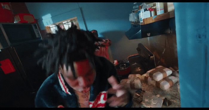 a man with dreadlocks standing in a kitchen