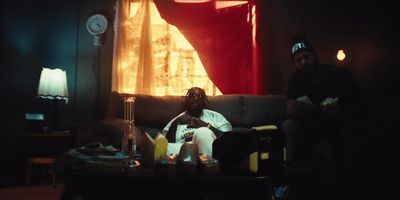 two men sitting on a couch in a dark room