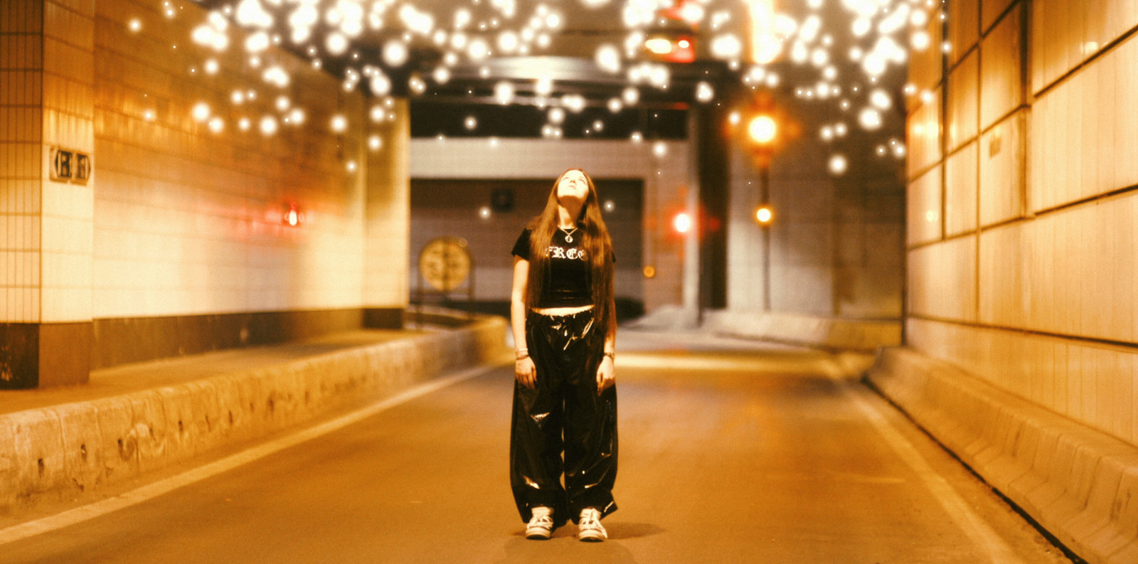 a woman standing in a hallway with lights on the ceiling