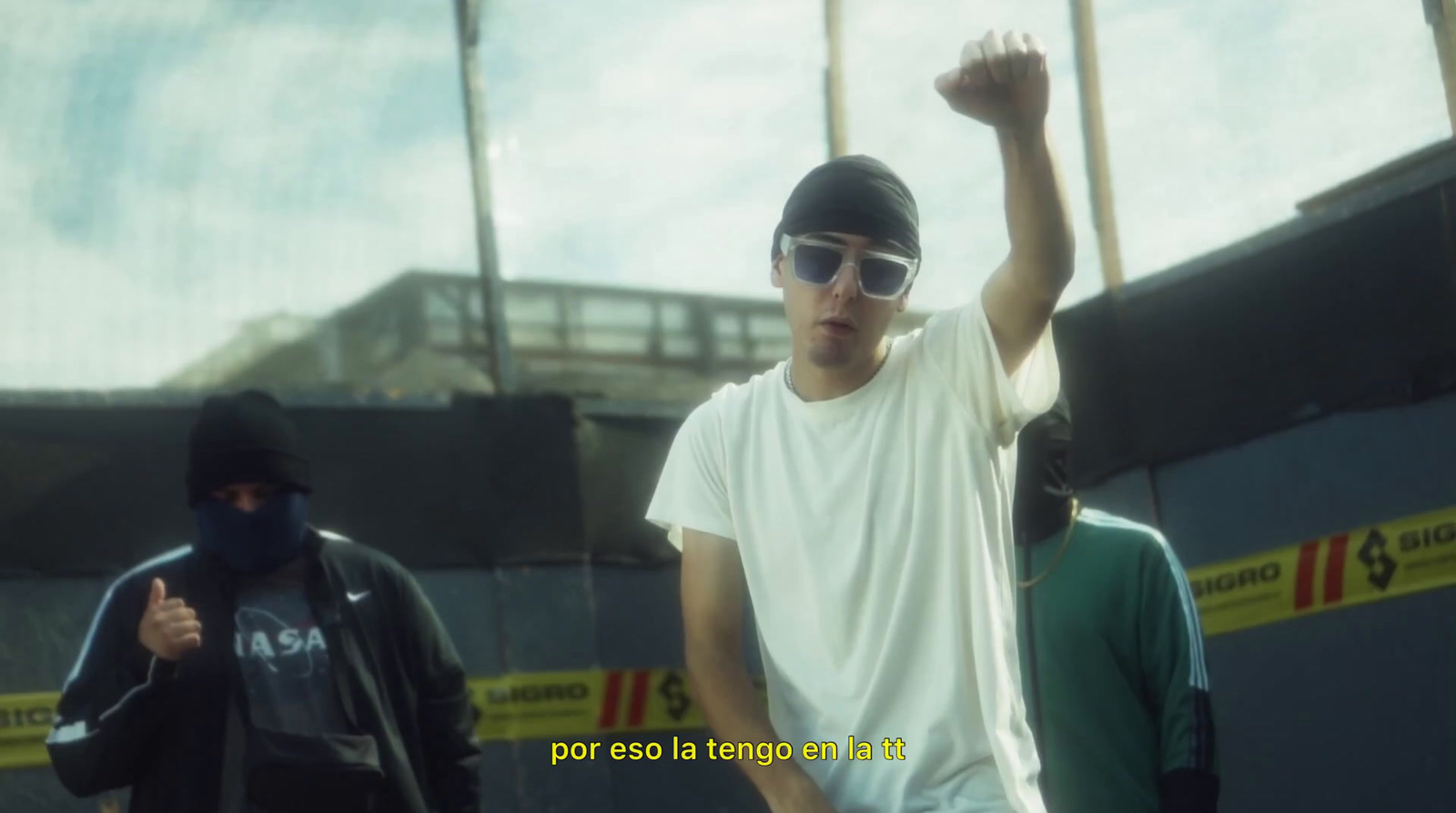 a man in a white t - shirt and sunglasses holding his fist up