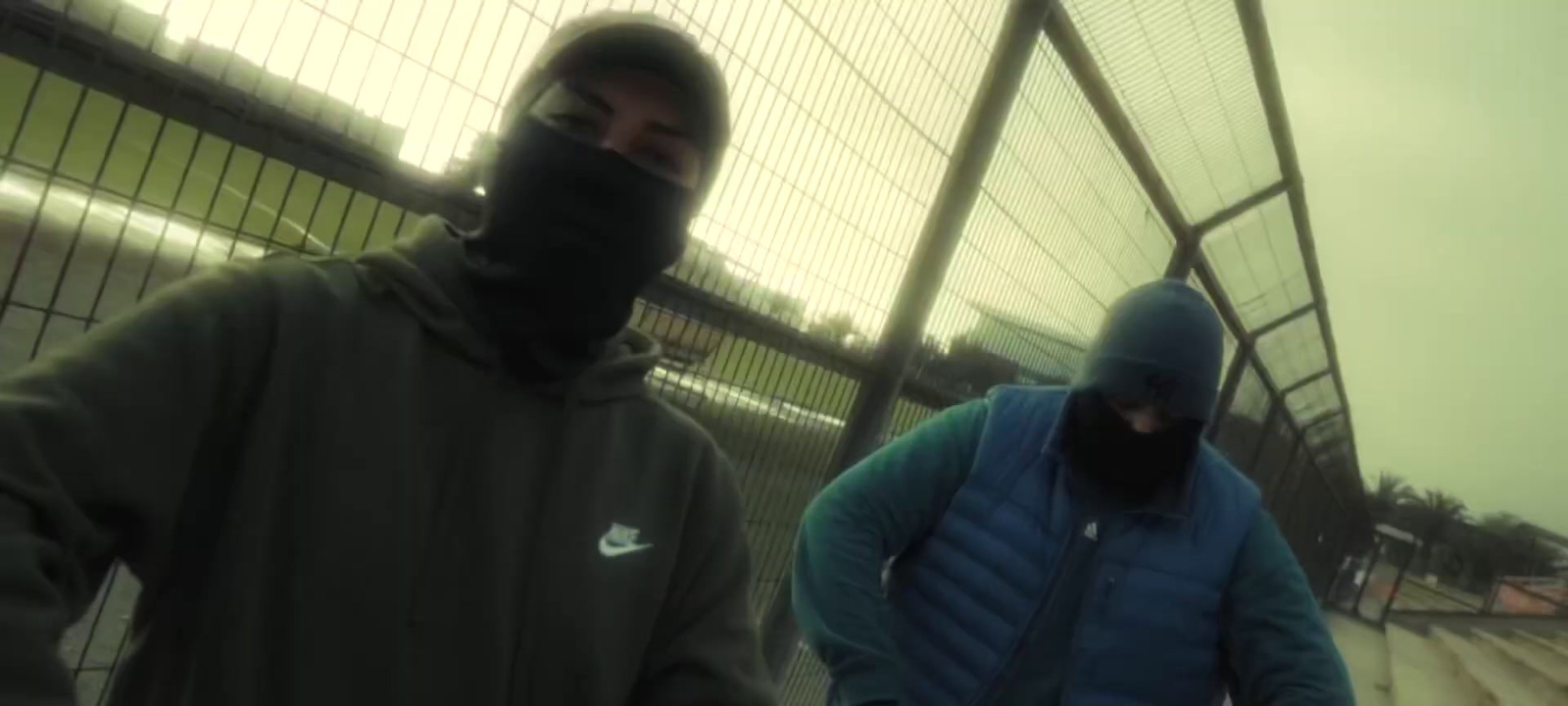 two men wearing face masks walking down a street