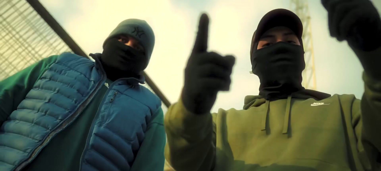 two men in black and green hoodies holding up their fingers